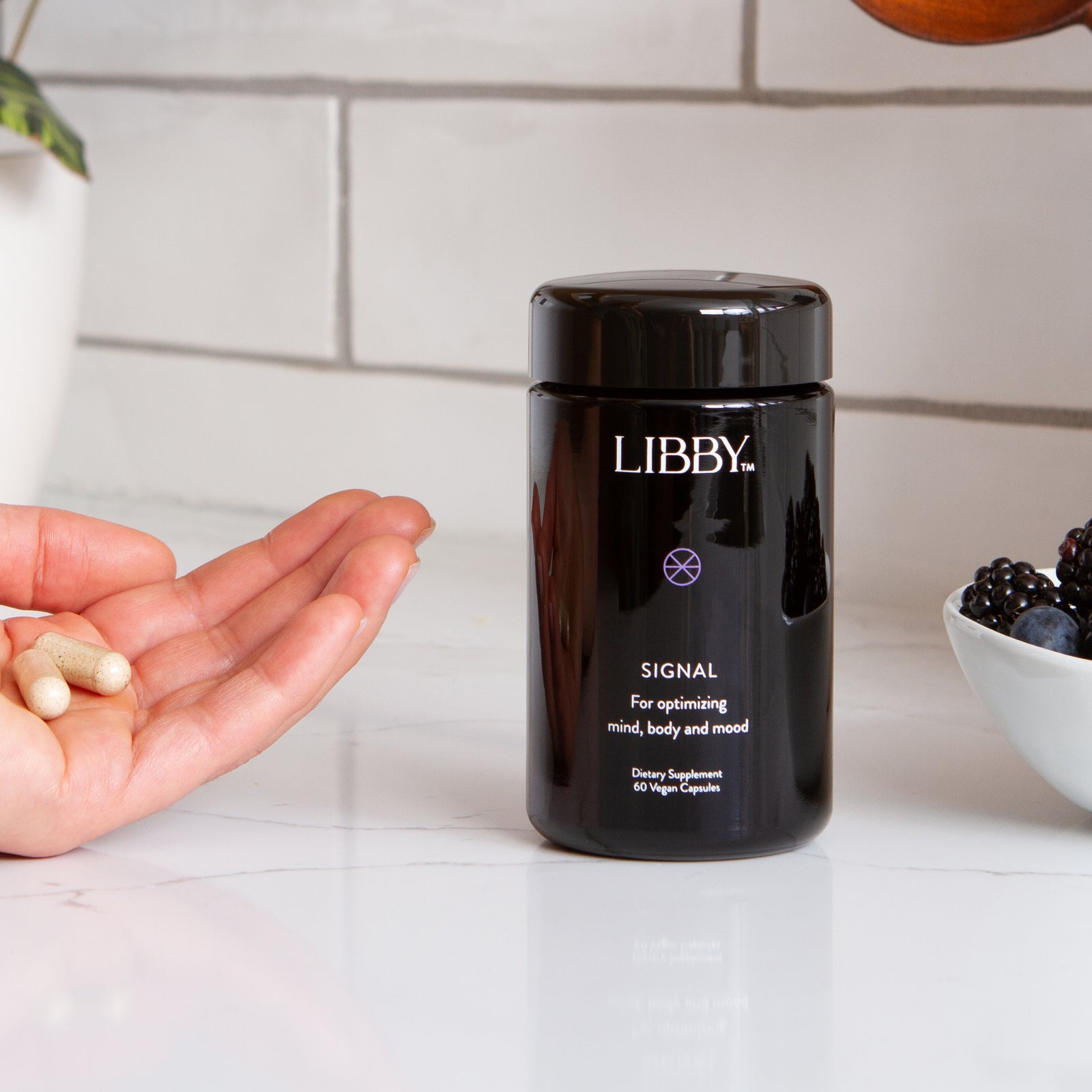 Libby supplement in hand next to black bottle