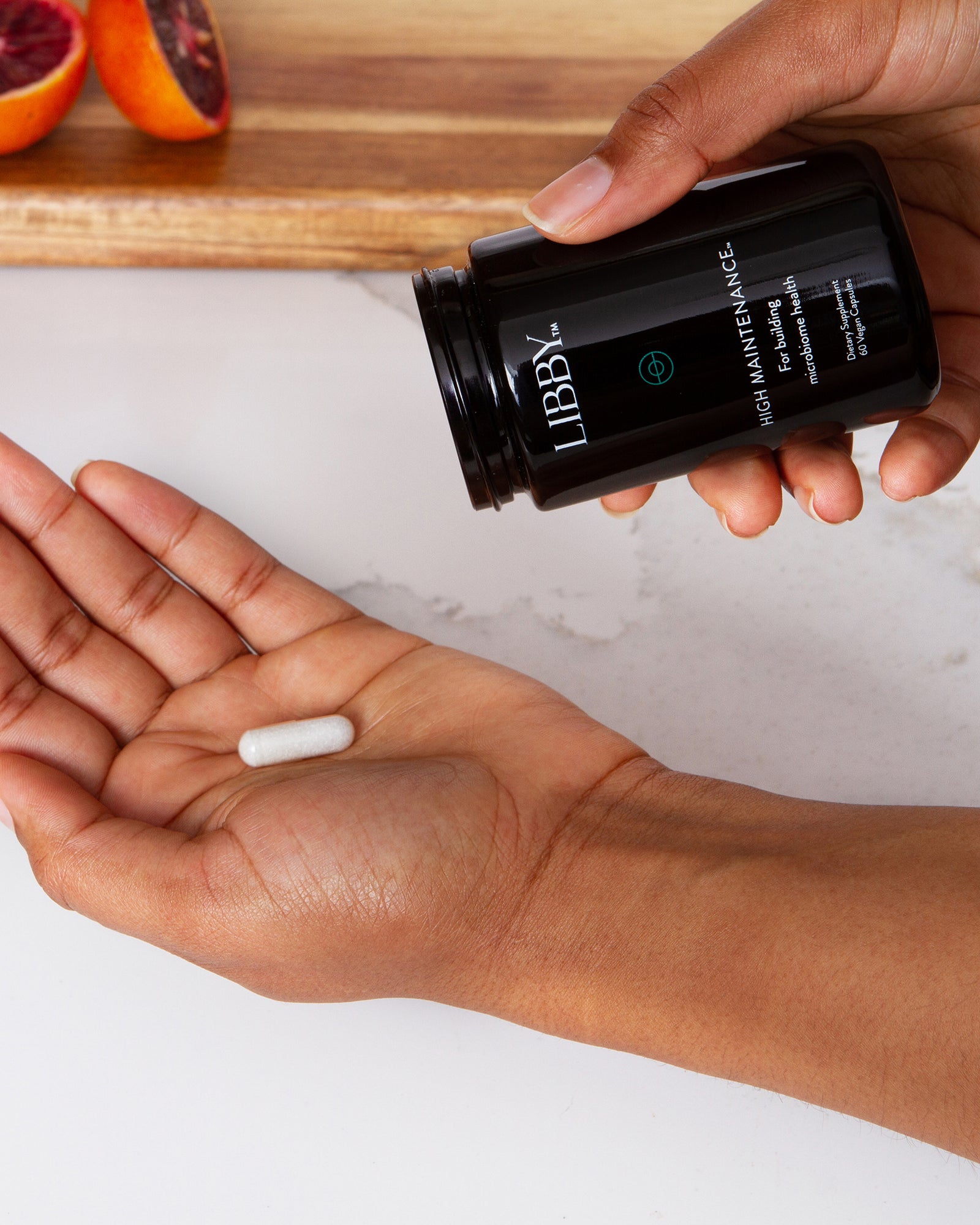 High Maintenance supplement bottle and hand.